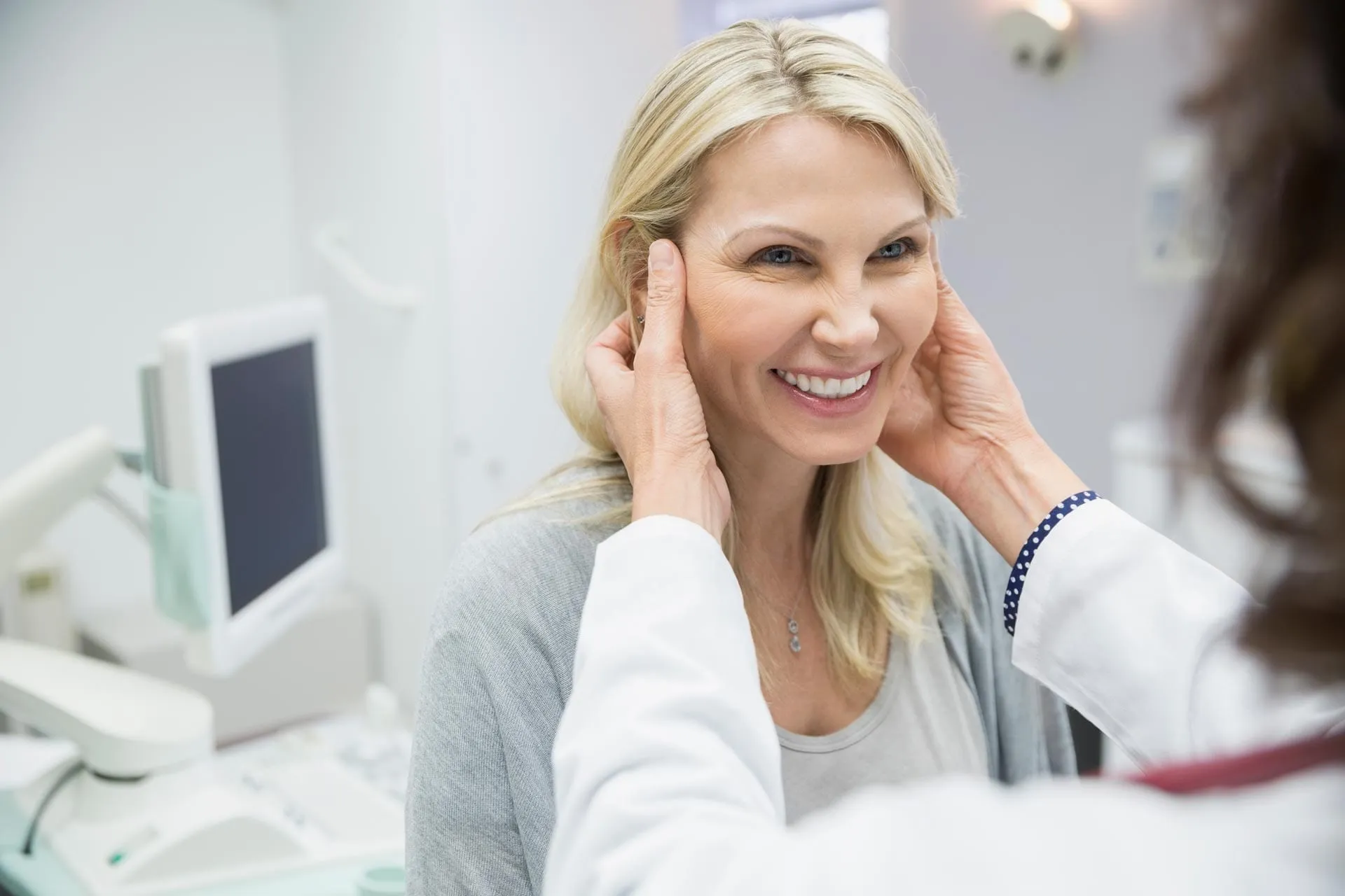 Plastic surgeon touching woman's face in examination room